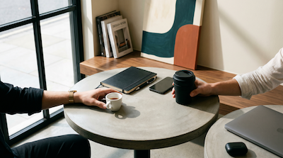 Zwei Hände an Espressotasse und Keepcup auf Marmortisch im urbanen Café — 15-Minuten Coffee Chat